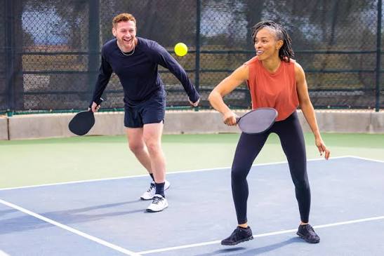 Two players smiling during a pickleball rally